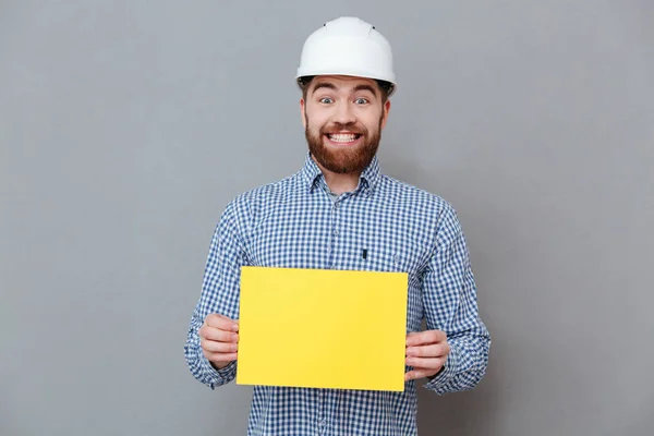 Веселий бородатий чоловік будівельник тримає копійку порожньою — стокове фото