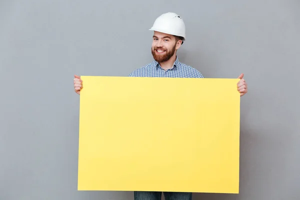 Щасливий молодий бородатий будівельник тримає дошку — стокове фото