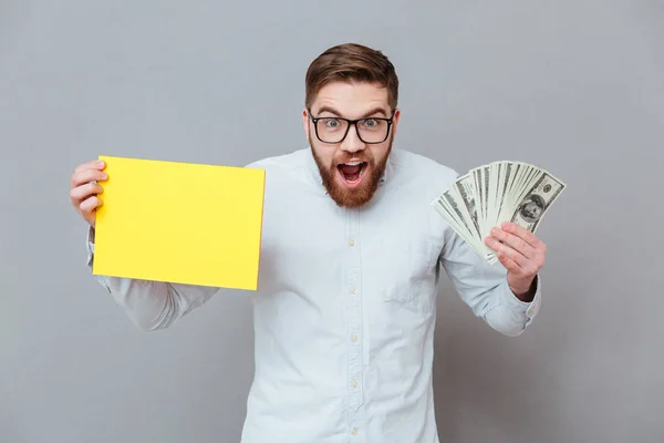Шокированный улыбающийся бизнесмен держит в руках копирайт пустой и деньги — стоковое фото
