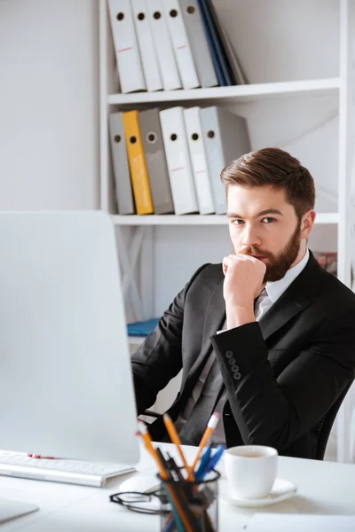 Бородатый бизнесмен, сидящий в офисе за компьютером — стоковое фото
