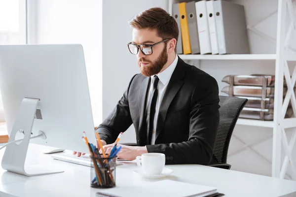 Beau jeune homme d'affaires barbu assis au bureau — Photo