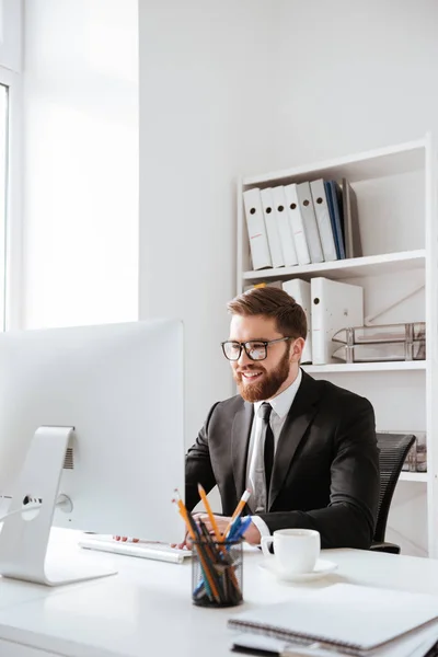 Knappe jonge bebaarde zakenman met behulp van computer. — Stockfoto