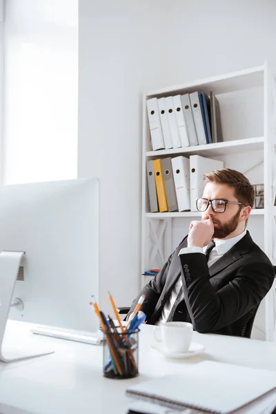 Aantrekkelijke jonge bebaarde zakenman zitten in kantoor — Stockfoto