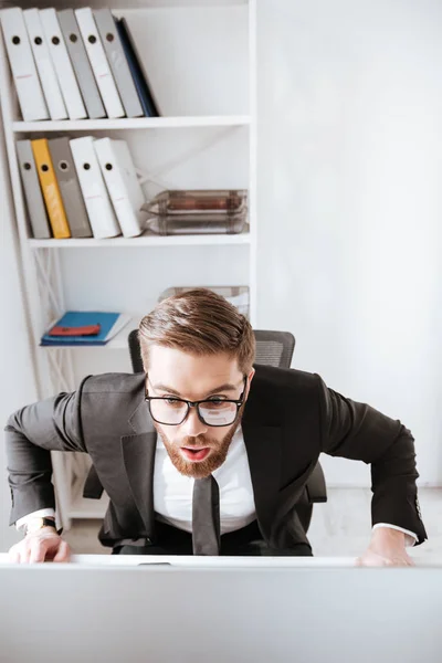 Empresario barbudo sorprendido mirando la computadora —  Fotos de Stock