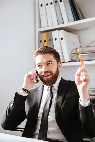 Hombre de negocios alegre hablando por teléfono y sosteniendo el lápiz . —  Fotos de Stock