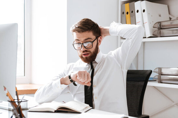 Shocked young businessman looking at watch.