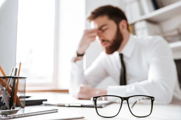 Confused young businessman sitting in office — Stock Photo, Image