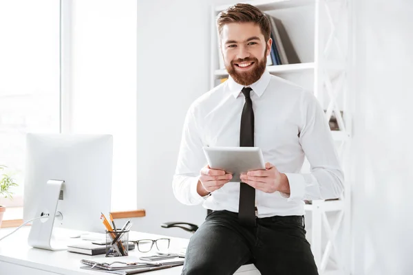 Homme d'affaires assis au bureau tout en tenant la tablette  . — Photo