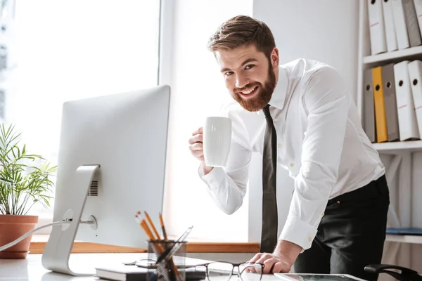 Atractivo joven empresario beber té y el uso de la computadora . — Foto de Stock