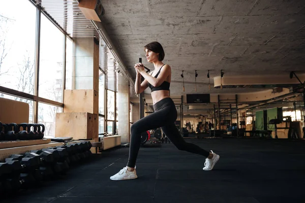 Mujer atleta haciendo ejercicio y haciendo sentadillas en el gimnasio —  Fotos de Stock