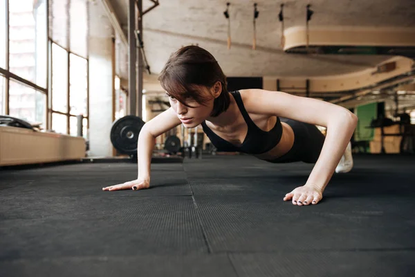 Fitness kvinna tränar och gör armhävningar i gymmet — Stockfoto