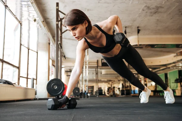 Atleta donna che fa esercizi con manubri in palestra — Foto Stock