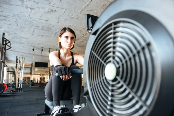 Vrouw atleet uit te werken met opleiding machine in sportschool — Stockfoto
