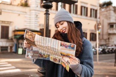 Gülümseyen harita kullanarak ve şehirde yürüyüş concetrated kadın