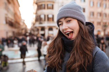 Ayakta ve şehirde göz kırpıyor neşeli kadın