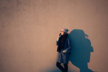 Kadın sıcak giysiler ayakta ve taalking üstünde hareket eden telefon