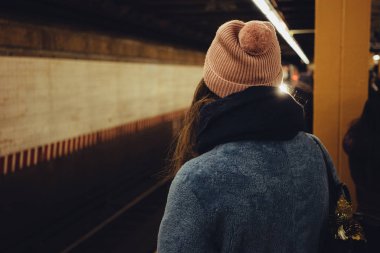 Metro bir tren için bekleyen genç kadın