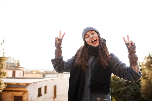 Весела молода жінка показує знак миру в місті — стокове фото