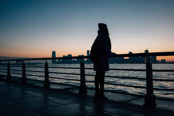 Silhouette de femme debout à la rampe sur un front de mer — Photo