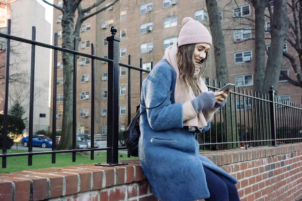 Mujer usando el teléfono móvil mientras está sentado en una calle de la ciudad —  Fotos de Stock