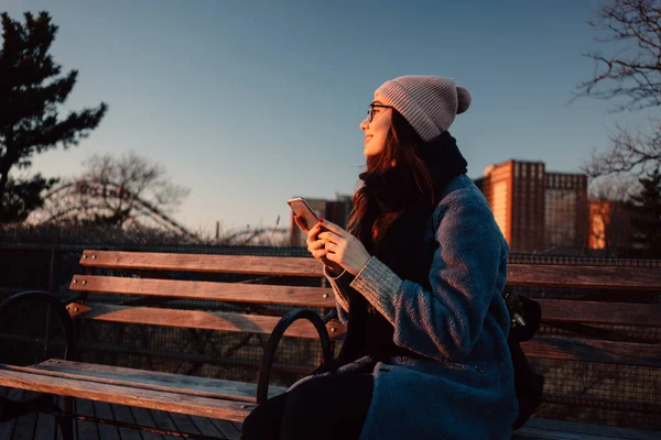 Lächelnde junge Frau im Mantel mit Handy — Stockfoto