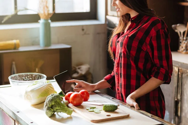 Imagem cortada de mulher em pé na cozinha com computador tablet — Fotografia de Stock