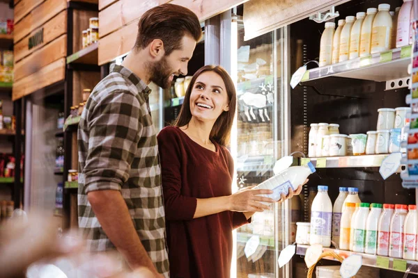 Пара розмовляє і купує молоко в продуктовому магазині — стокове фото