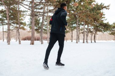 Karda koşan adam ormandaki kış yolu kaplıydı.