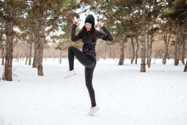 Sporcu genç kadın karlı şehir parkında egzersiz