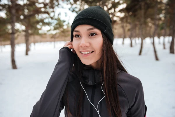 Årets idrottskvinna i hatt lyssnar musik med hörlurar utomhus — Stockfoto