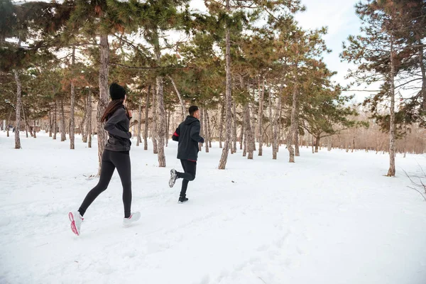 Vista de um jovem casal fitness correndo na floresta — Fotografia de Stock