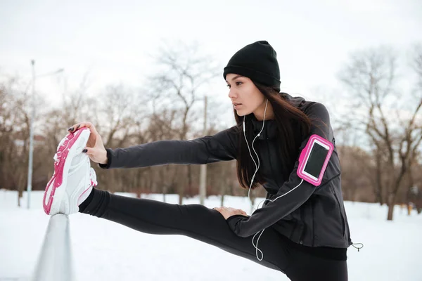 Mujer con brazalete que estira las piernas antes de correr al aire libre — Foto de Stock