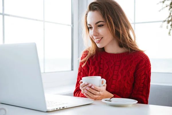 Mujer feliz usando el ordenador portátil y beber café en la cafetería — Foto de Stock