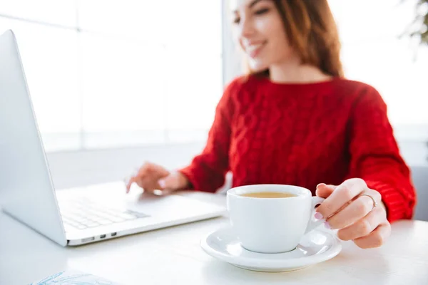 Sorrindo mulher bebendo café e trabalhando com laptop no café — Fotografia de Stock