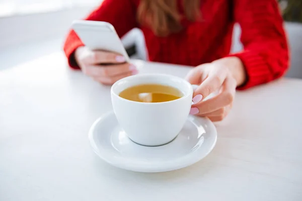 Image recadrée d'une dame assise dans un café tenant du thé . — Photo