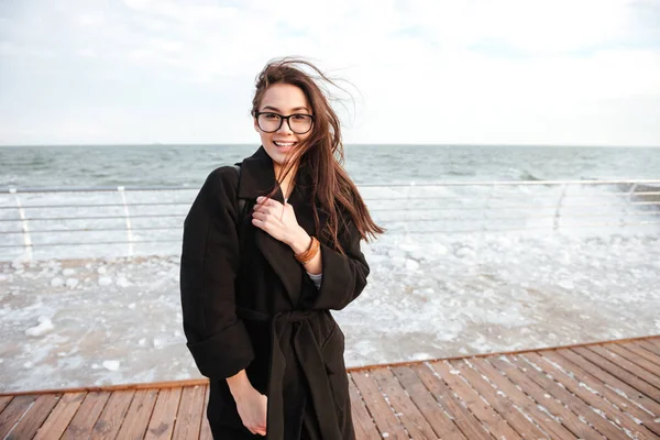 Joyeux jeune femme mignonne dans des lunettes sur jetée en hiver — Photo