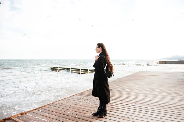 Woman standing on pier and looking at sea in winter — Stock Photo, Image