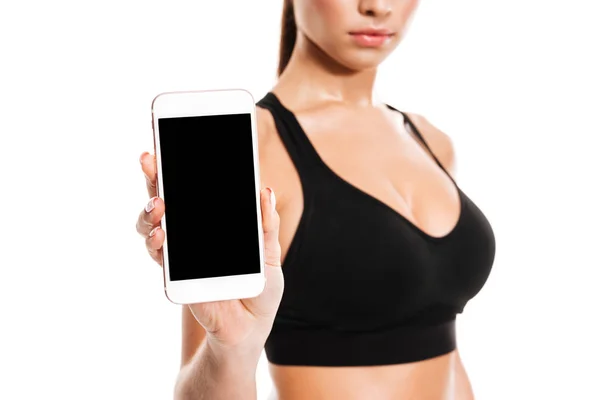 Молодая довольно фитнес-женщина показывает чистый экран мобильного телефона — стоковое фото