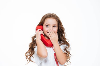 Gülümseyen ve kırmızı telefonla konuşurken mutlu kıvırcık küçük kız