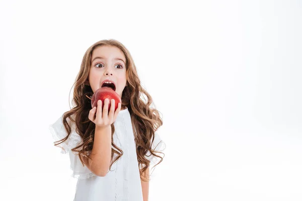 Cute little girl holding and eating red apple — Stock Photo, Image