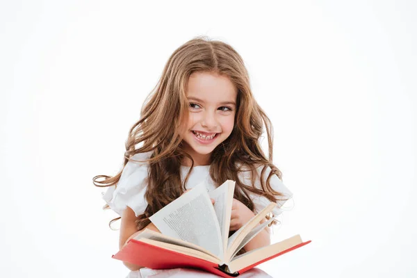 Веселая маленькая девочка смеется и читает книгу — стоковое фото