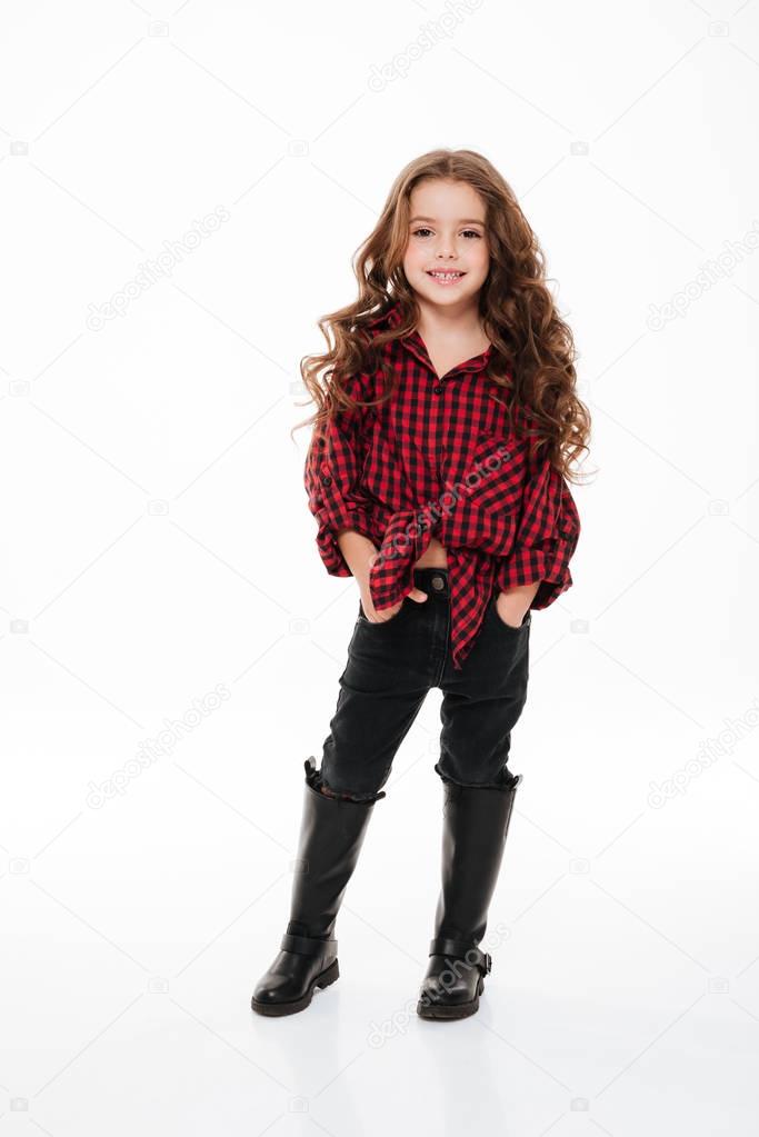 Pretty curly little girl in plaid shirt standing and posing