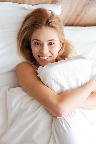 Вертикальне зображення усміхненої жінки, що обіймається подушкою — стокове фото