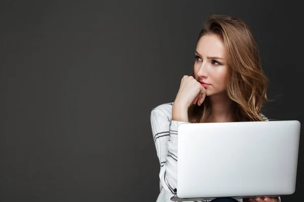 Serious lady using laptop over dark background