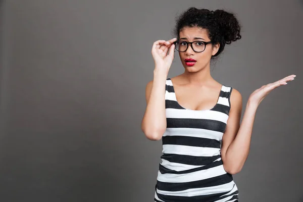 Verwirrte junge Frau mit Brille hält Kopierplatz auf Handfläche — Stockfoto