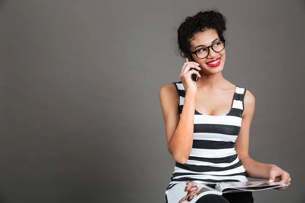 Sorridente donna felice che parla sul cellulare mentre tiene la rivista — Foto Stock