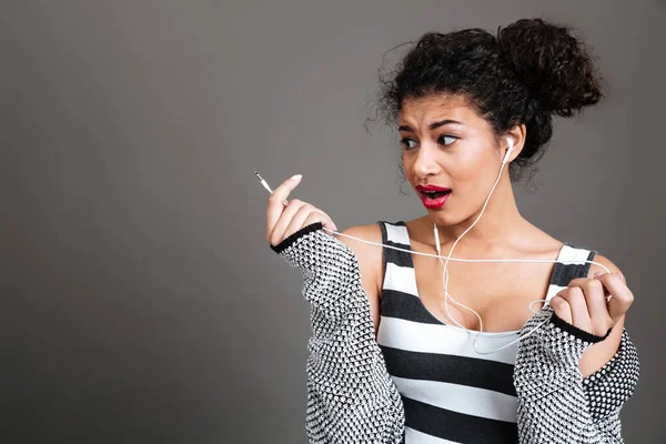 Mladí zmatený afro americký žena držící rozbité sluchátka — Stock fotografie
