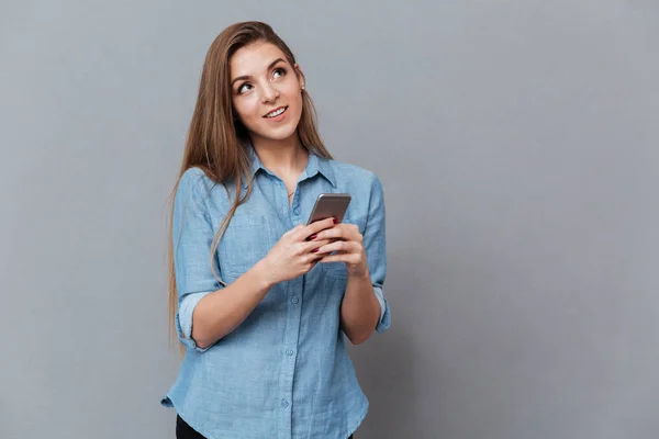 Nadenkend vrouw in hemd met behulp van de telefoon — Stockfoto