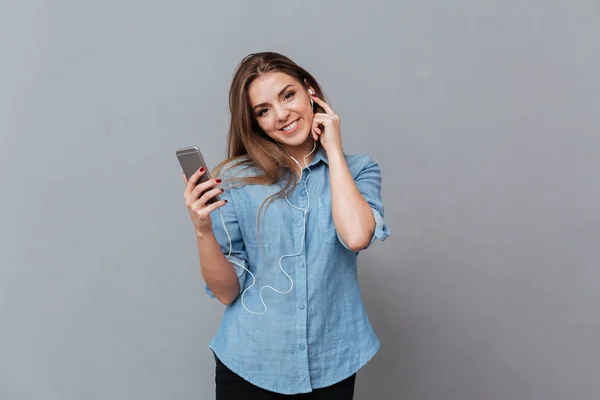 Sorrindo Mulher de camisa ouvindo música no telefone — Fotografia de Stock