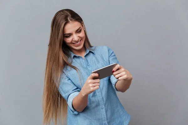 Lachende vrouw in hemd afspelen op telefoon — Stockfoto